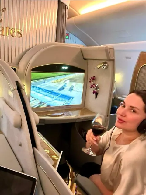 Clea brindando con vino tinto en la First Class de Emirates